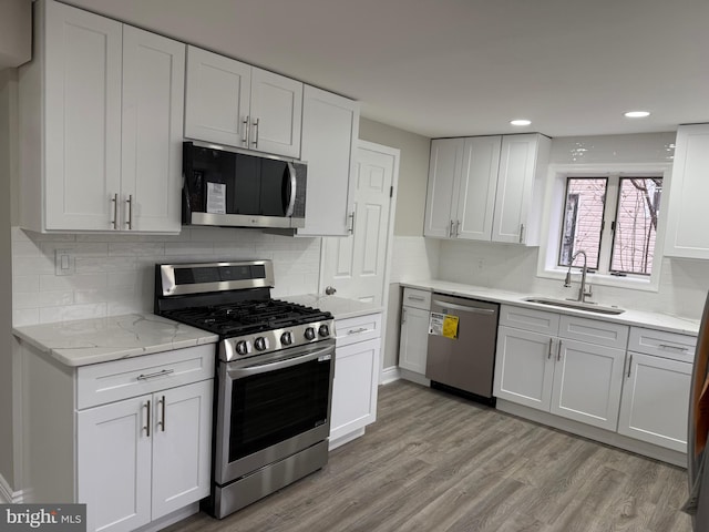 kitchen with white cabinetry, sink, light wood-type flooring, and appliances with stainless steel finishes