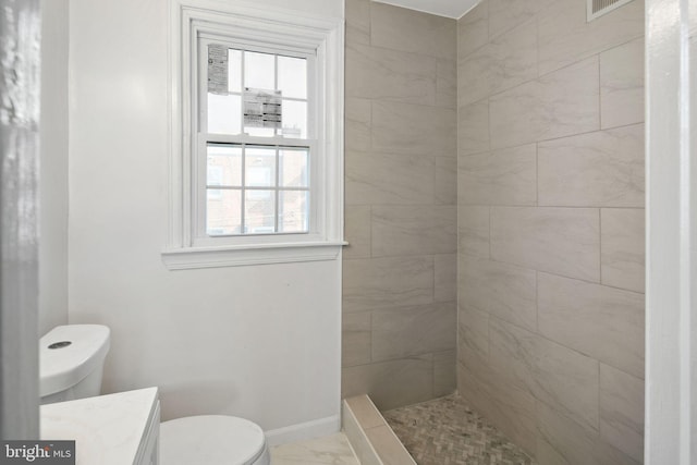 bathroom with vanity, toilet, and tiled shower