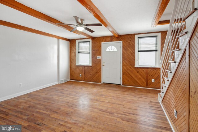 foyer entrance with wooden walls, plenty of natural light, and light wood-type flooring