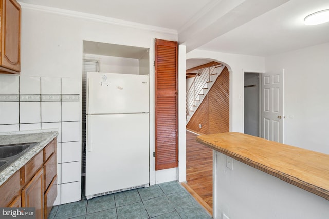 kitchen featuring decorative backsplash, crown molding, white fridge, and light hardwood / wood-style floors