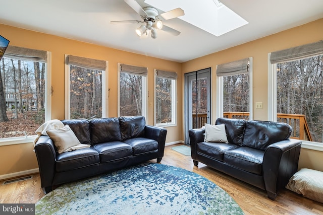 living room featuring a skylight, a wealth of natural light, and light hardwood / wood-style flooring