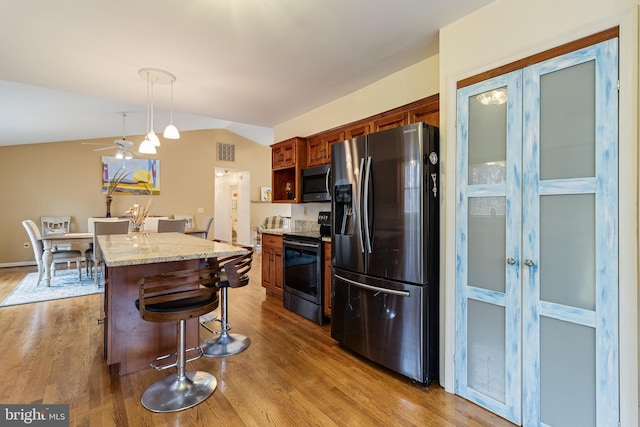 kitchen with wood-type flooring, hanging light fixtures, vaulted ceiling, and appliances with stainless steel finishes