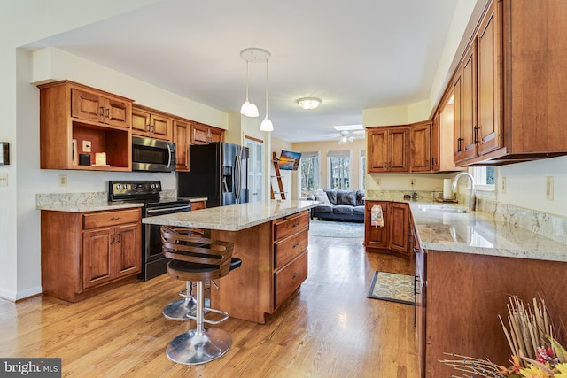 kitchen with hanging light fixtures, a center island, stainless steel appliances, and light hardwood / wood-style floors