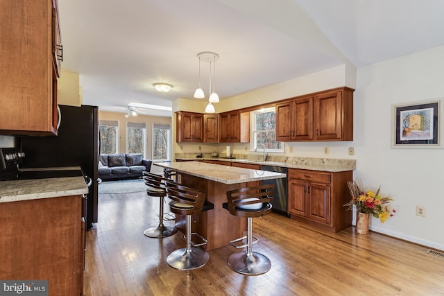 kitchen featuring dishwasher, decorative light fixtures, light hardwood / wood-style flooring, and a healthy amount of sunlight