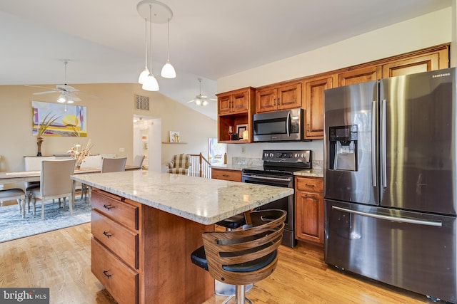 kitchen featuring light hardwood / wood-style flooring, pendant lighting, vaulted ceiling, a kitchen island, and appliances with stainless steel finishes