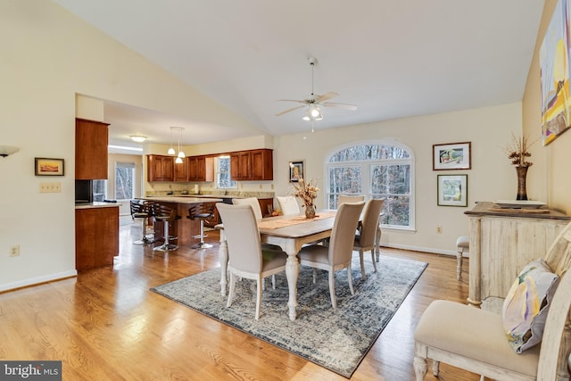 dining room with ceiling fan, vaulted ceiling, and light hardwood / wood-style flooring