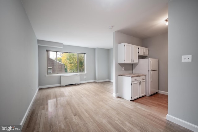 kitchen with white cabinets, radiator heating unit, light wood-type flooring, and white refrigerator