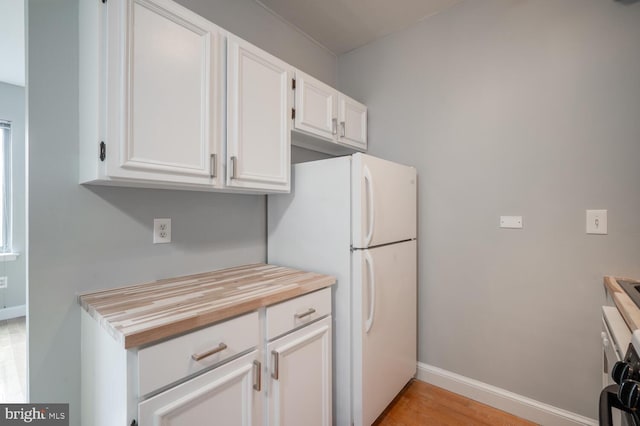 kitchen featuring wood counters, white refrigerator, light hardwood / wood-style floors, and white cabinetry