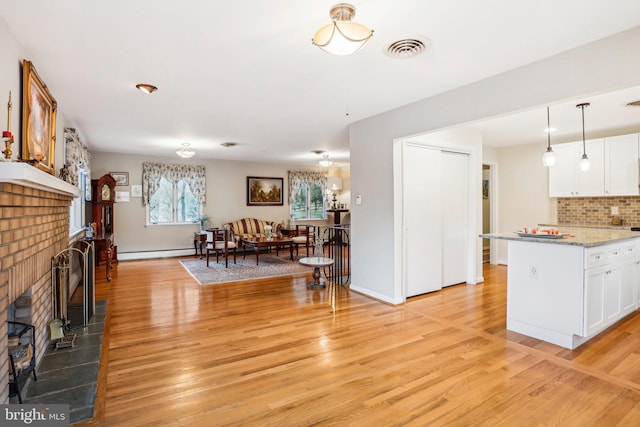 living room with a baseboard heating unit, light wood-type flooring, and a brick fireplace