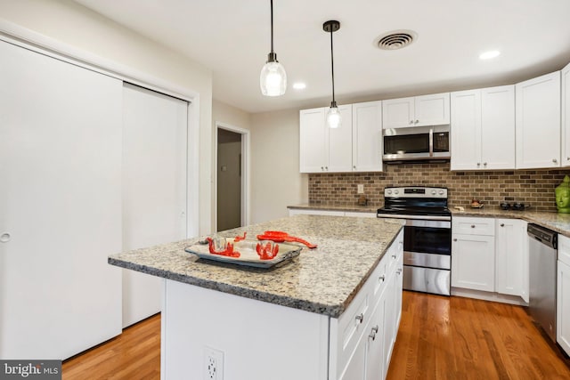 kitchen featuring white cabinets, a kitchen island, stainless steel appliances, and light wood-type flooring