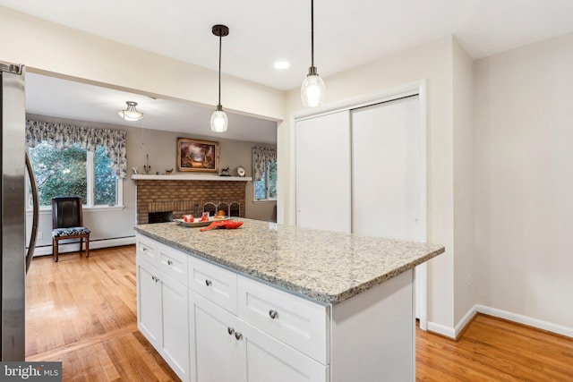 kitchen featuring pendant lighting, white cabinets, light stone countertops, light wood-type flooring, and a baseboard radiator