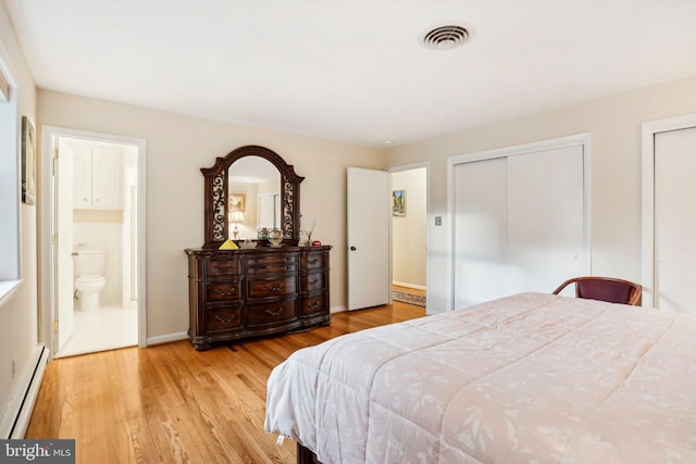 bedroom with ensuite bathroom, a baseboard heating unit, and light wood-type flooring