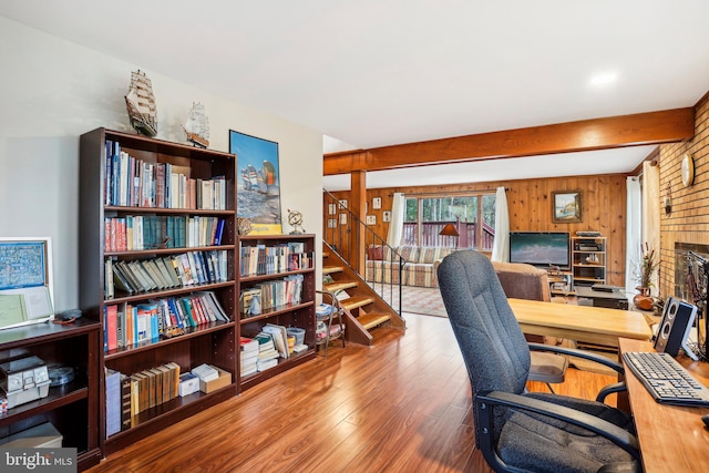 office space featuring hardwood / wood-style floors, wood walls, a fireplace, and beamed ceiling