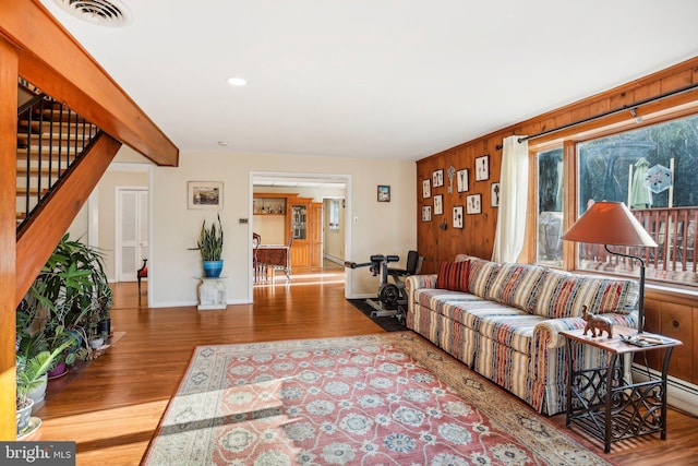 living room featuring beamed ceiling, wood-type flooring, and wooden walls