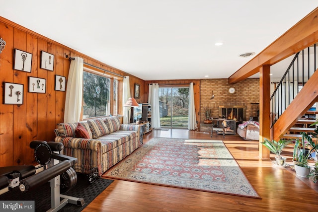 living room with a fireplace, light wood-type flooring, and wood walls