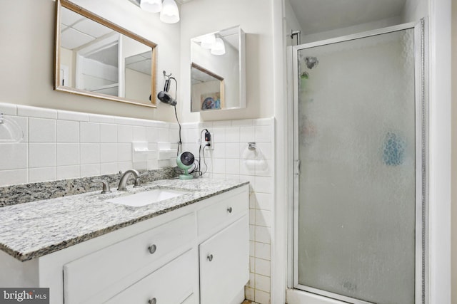 bathroom featuring vanity, an enclosed shower, and tile walls