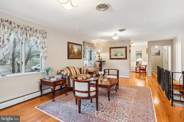 living room with a baseboard heating unit and light hardwood / wood-style flooring