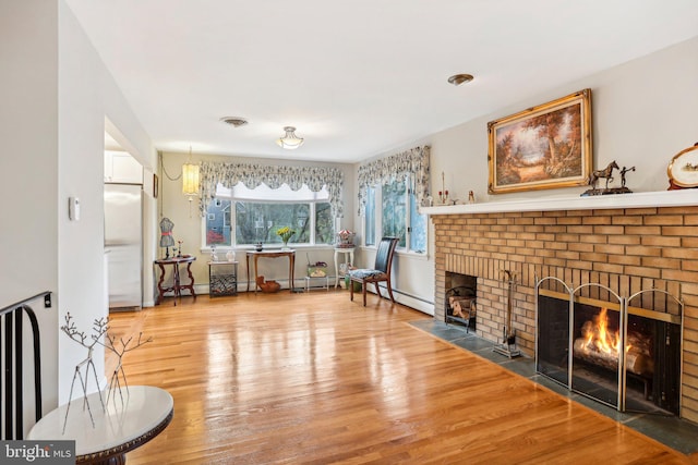 sitting room featuring a fireplace, a baseboard radiator, and hardwood / wood-style flooring