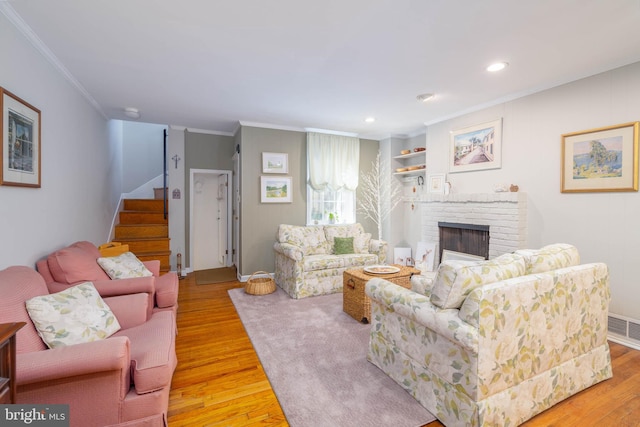 living room featuring crown molding, light wood-type flooring, and a fireplace