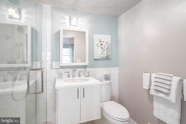 bathroom with toilet, vanity, tile walls, and walk in shower