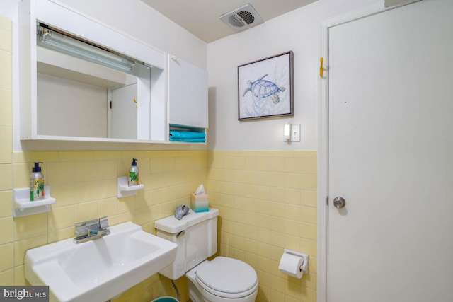 bathroom featuring sink, tile walls, and toilet