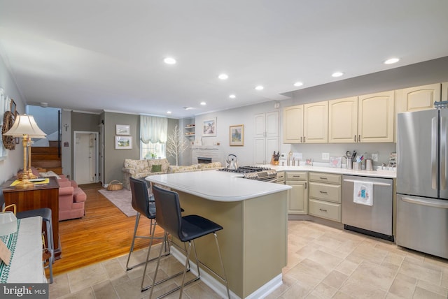 kitchen featuring a breakfast bar, cream cabinetry, light wood-type flooring, and appliances with stainless steel finishes