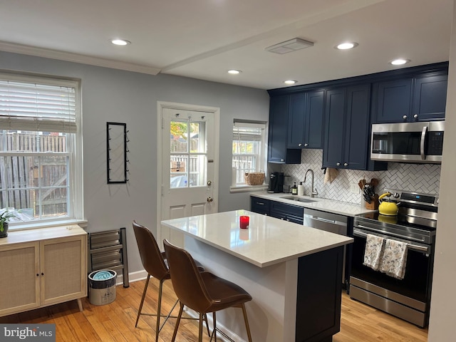 kitchen featuring blue cabinetry, appliances with stainless steel finishes, light wood-type flooring, and sink