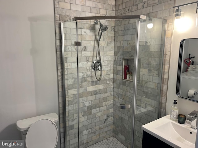 bathroom featuring toilet, an enclosed shower, washer / clothes dryer, and vanity