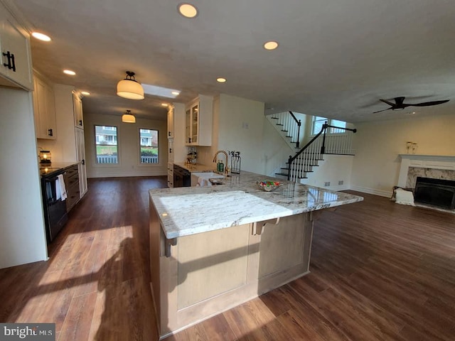 kitchen with a breakfast bar, dark wood-type flooring, black range with electric stovetop, light stone counters, and white cabinetry