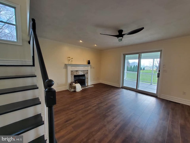 unfurnished living room with a fireplace, ceiling fan, and dark wood-type flooring