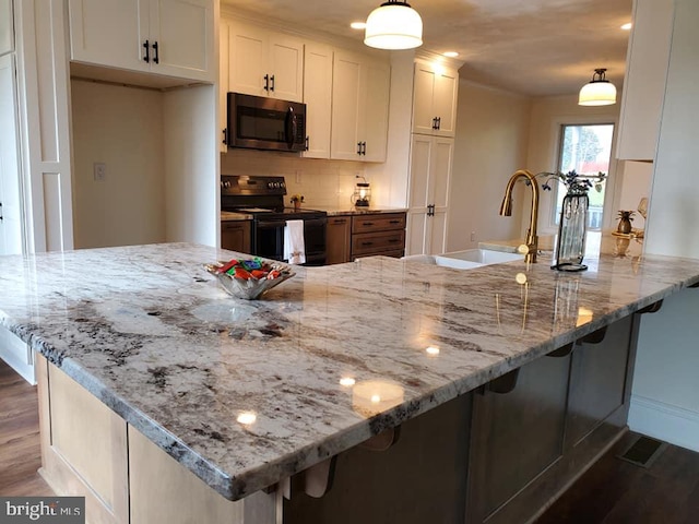 kitchen featuring black electric range, white cabinets, light stone counters, and hanging light fixtures