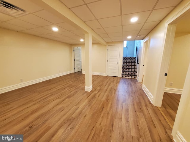 basement featuring light hardwood / wood-style flooring and a drop ceiling