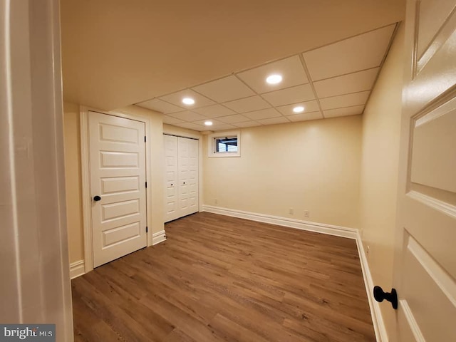 basement with a paneled ceiling and dark wood-type flooring