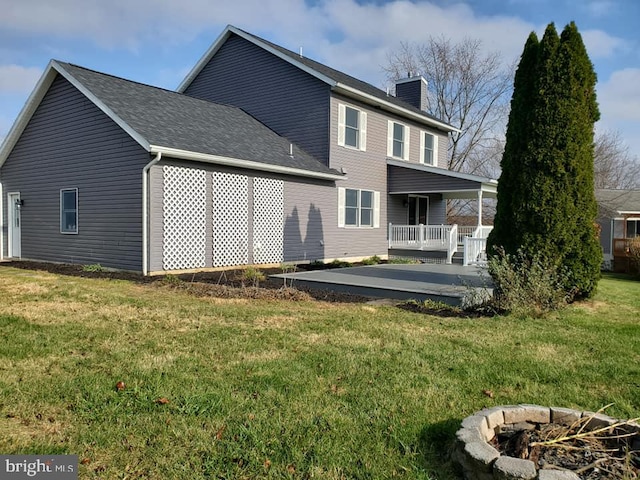 back of property featuring a lawn, an outdoor fire pit, and a wooden deck