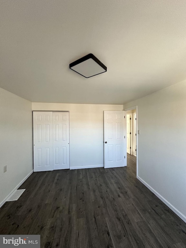 unfurnished bedroom with dark hardwood / wood-style floors and a closet