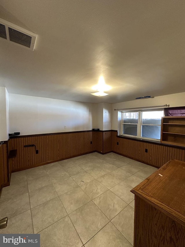 spare room with light tile patterned flooring, a water view, and wood walls