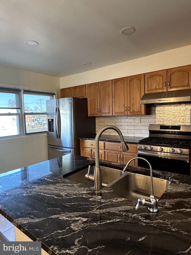 kitchen featuring backsplash, dark stone countertops, sink, and appliances with stainless steel finishes