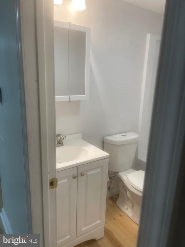 bathroom featuring toilet, vanity, and hardwood / wood-style flooring