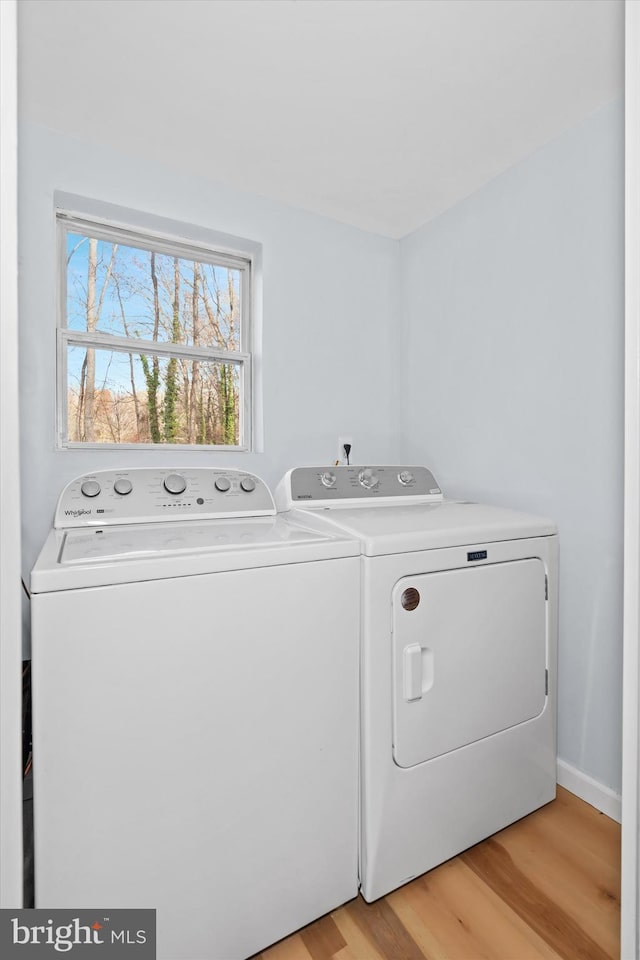 clothes washing area featuring washer and clothes dryer and light hardwood / wood-style floors