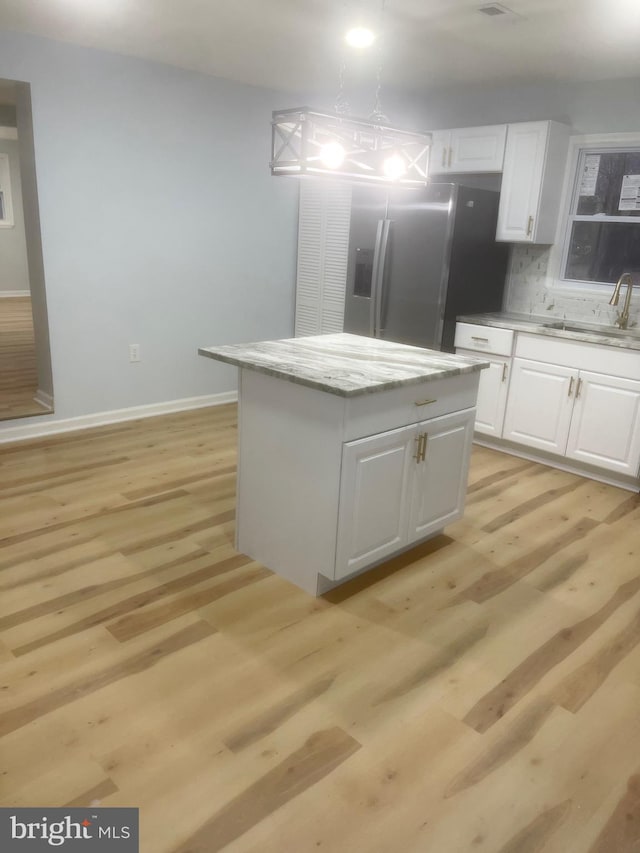 kitchen with white cabinets, stainless steel fridge with ice dispenser, light hardwood / wood-style flooring, and a kitchen island