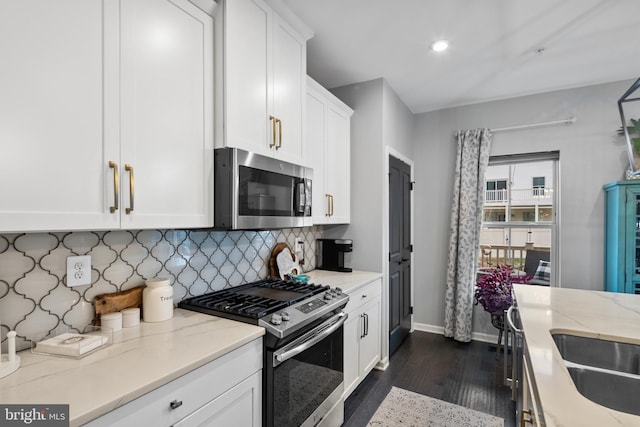 kitchen featuring light stone countertops, appliances with stainless steel finishes, tasteful backsplash, white cabinets, and dark hardwood / wood-style floors