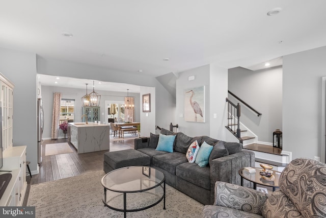 living room with an inviting chandelier, light hardwood / wood-style flooring, and sink