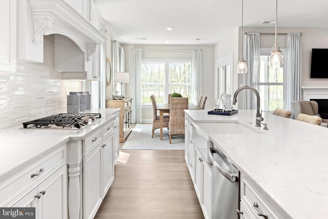 kitchen with light hardwood / wood-style flooring, decorative light fixtures, light stone counters, white cabinetry, and stainless steel appliances