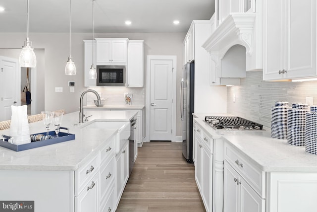 kitchen featuring white cabinetry, hanging light fixtures, stainless steel appliances, and light hardwood / wood-style floors