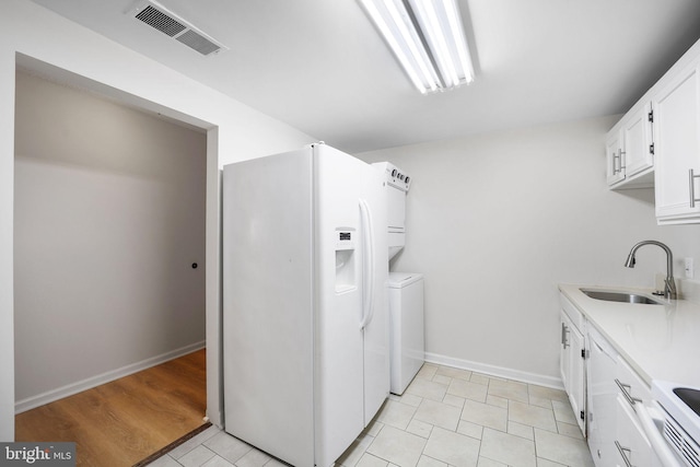 clothes washing area featuring light tile patterned floors, washer and clothes dryer, and sink