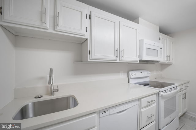 kitchen with sink, white cabinets, light tile patterned flooring, and white appliances