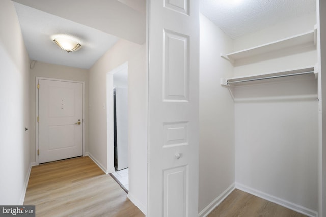 hallway featuring a textured ceiling and light hardwood / wood-style floors