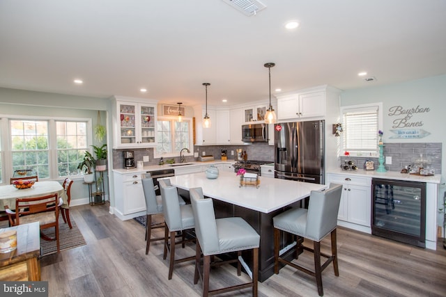 kitchen featuring a center island, wine cooler, light hardwood / wood-style floors, white cabinetry, and stainless steel appliances