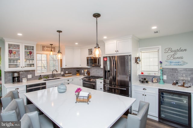 kitchen with appliances with stainless steel finishes, a healthy amount of sunlight, a kitchen bar, and wine cooler