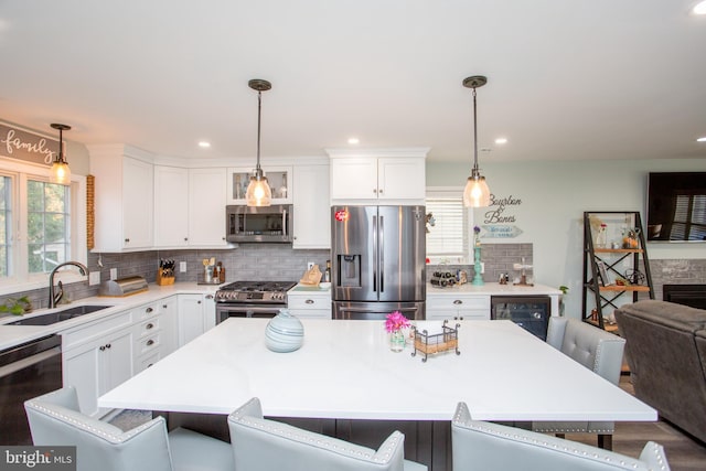 kitchen with appliances with stainless steel finishes, a breakfast bar, a kitchen island, sink, and white cabinetry